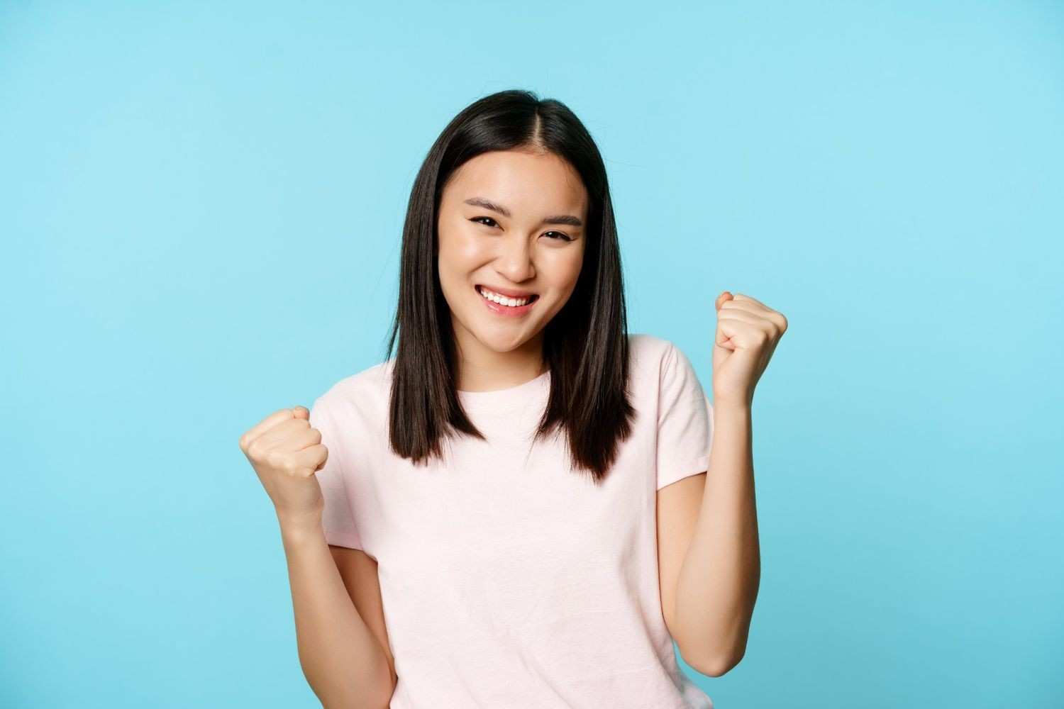 enthusiastic-cute-asian-girl-winning-rejoicing-from-great-news-victory-dance-smiling-pleased-standing-blue-background (1)